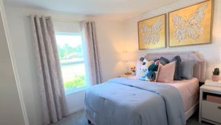 A cozy bedroom featuring butterfly artwork, soft pastel bedding, and ample natural light from a large window.