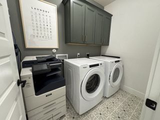 Model Home A functional laundry room featuring a washer, dryer, copier, and stylish cabinetry with patterned tile flooring.
