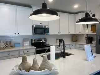 A modern kitchen with sleek black fixtures, white cabinetry, and contemporary lighting.
