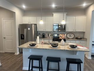 A modern kitchen with granite countertops, sleek stainless steel appliances, and elegant pendant lights, featuring a cozy island seating area.