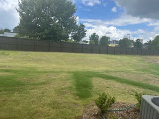 Expansive grassy yard with mature trees and a tall fence in Battle Bridge by DRB Homes (Raleigh, NC).