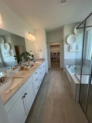 Model Home A sleek bathroom with double vanity, spacious mirrors, and a glass-enclosed shower.