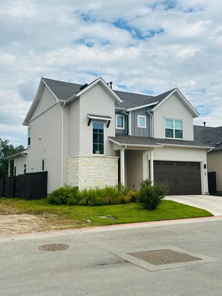 Street view A modern two-story home with stone accents in Cross Creek by Brohn Homes (Cedar Park, TX).