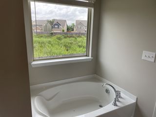 A serene bathroom featuring a large soaking tub and a picturesque view of the outdoors.