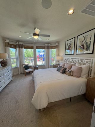 A cozy bedroom featuring a large bed, modern artwork, and a bright view through wide windows with elegant curtains.