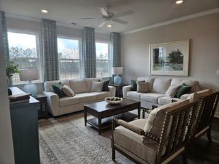 Model Home A cozy living room with neutral tones, large windows, and classic furnishings in Oak Ridge Meadows by D.R. Horton (Locust Grove, GA).
