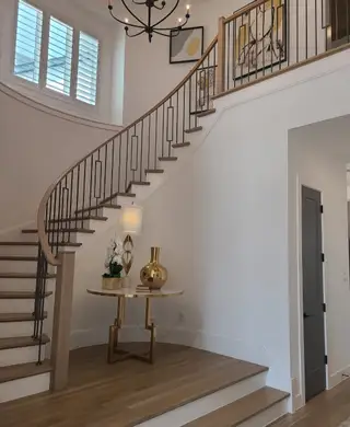 Model Home A grand staircase with elegant railing, curved design, and chic decor accentuates this stylish foyer.