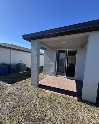 A modern home with a cozy patio and sliding glass doors in Bradbury Creek - Signature Series by Meritage Homes (Haines City, FL).