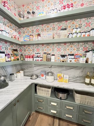 A vibrant pantry features patterned wallpaper, open shelves, and elegant marble countertops for ample storage.