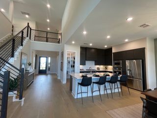 A spacious, modern kitchen with sleek dark cabinets, an inviting island with seating, and elegant hardwood floors.