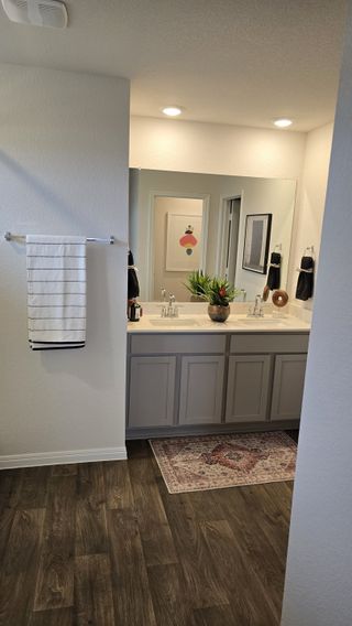 A modern bathroom with a dual-sink vanity, sleek black fixtures, and wood-look flooring for a contemporary touch.