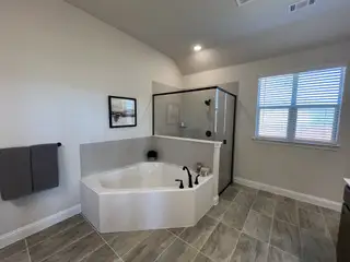 A modern bathroom featuring a corner bathtub, glass shower enclosure, and elegant tile flooring.