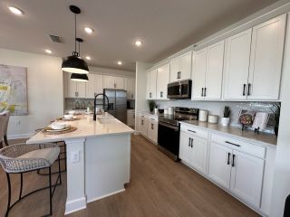 A sleek kitchen with white cabinets, stainless steel appliances, and a spacious island with seating.