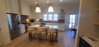 A modern kitchen featuring pendant lights, a large island, stainless appliances, and elegant cabinetry.
