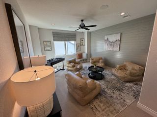 Street view A cozy living area with plush seating, textured rug, modern fan, and gaming table, perfect for relaxation and entertainment.