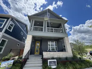 A modern two-story home with stylish stone accents and vibrant landscaping in The Twilight at Goodnight Ranch by David Weekley Homes (Austin, TX).