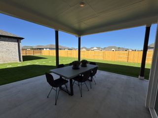 A spacious covered patio with a sleek table and chairs overlooking a fenced backyard. Perfect for outdoor dining and relaxation.