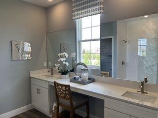 A bright bathroom featuring dual sinks, sleek fixtures, and elegant decor with natural light streaming through a large window.