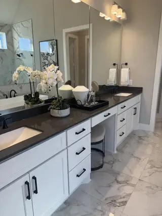 A luxurious bathroom with dual sinks, sleek gray countertops, and elegant marble flooring.