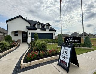 A charming white brick home with dark accents and lush landscaping in Sienna 65' by Shea Homes (Missouri City, TX).