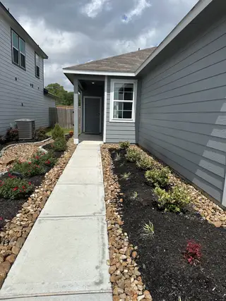 A charming gray home with manicured landscaping in Maple Heights by Century Communities (Porter Heights, TX).
