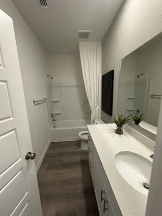 A modern bathroom with elegant wood flooring, a sleek white vanity, and a classic bathtub for a serene atmosphere.