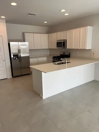 A sleek kitchen with white cabinetry, stainless steel appliances, and a spacious island with elegant lighting.