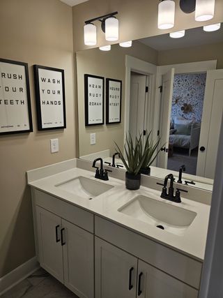 Model Home A stylish double vanity bathroom with sleek black fixtures, framed mirrors, and crisp white cabinetry for a modern touch.
