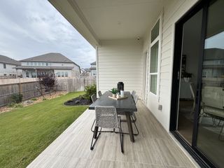 Model Home A cozy patio with sleek tile flooring, a modern dining table, and a lush green backyard. Perfect for outdoor gatherings.
