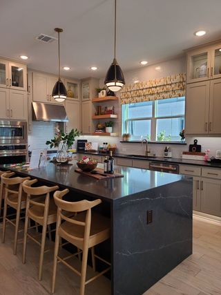 Stylish kitchen featuring sleek cabinetry, modern pendant lighting, and a dark island with wooden bar stools.
