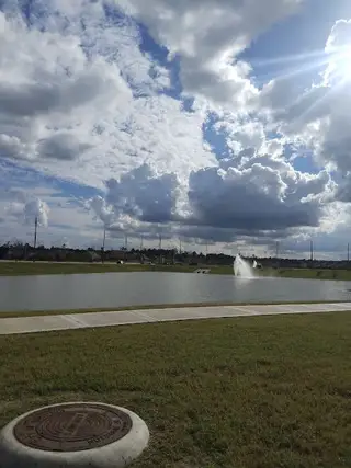 Community Amenities A picturesque lake with a fountain in Lakewood Pines Trails by KB Home (Houston, TX), offering peaceful water views.