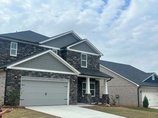 A charming grey stone home with a spacious driveway in Creekside at Oxford Park by Meritage Homes (Fairburn, GA).
