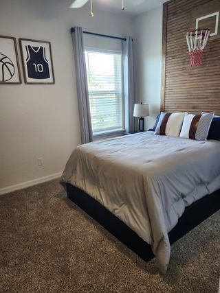 A cozy bedroom with a sporty theme, featuring basketball decor, a soft gray bedspread, and warm natural light through the window.