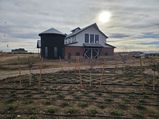 A modern farmhouse with dark siding and a metal roof in Farmlore by Century Communities (Brighton, CO).