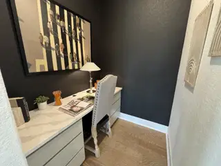 A chic pocket office with sleek built-in desk, dark accent wall, and contemporary decor in Veramendi by Coventry Homes (New Braunfels, TX).