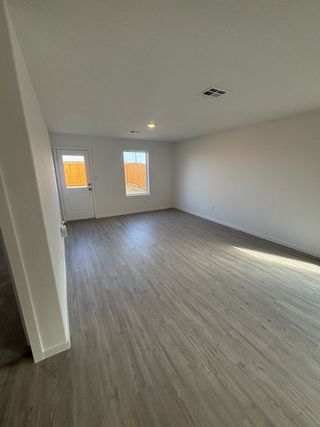 A spacious room with sleek wood flooring, neutral walls, and a door leading to the backyard, perfect for versatile design.