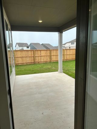Model Home A cozy covered patio with a concrete floor, offering a view of a fenced backyard and neighboring homes.