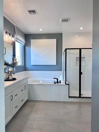 A modern bathroom featuring a glass-enclosed shower, sleek white tub, and stylish vanity with elegant fixtures.
