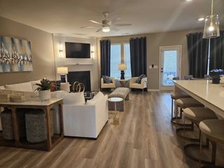 An inviting living room with a fireplace, modern decor, and wood flooring in Kingston by DRB Homes (Locust Grove, GA).