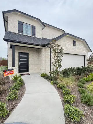 A modern white brick home with black accents and lush landscaping in Westridge by CastleRock Communities (McKinney, TX).