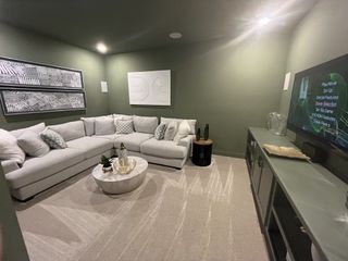 Model Home A stylish media room with deep green walls, a plush sectional, and built-in entertainment.
