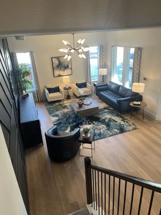 Model Home A spacious living room with modern lighting, a comfortable seating area, and a stylish rug, offering plenty of natural light.