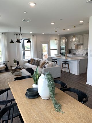 A stunning open living and dining area featuring contemporary furniture, warm lighting, and large windows bringing in natural light.