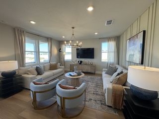 Model Home A cozy living room with neutral sofas, modern artwork, and elegant lighting, offering a warm and inviting atmosphere.