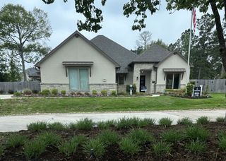 A beautiful stone-accented home with manicured landscaping in Stewart’s Forest by Sitterle Homes (Conroe, TX).