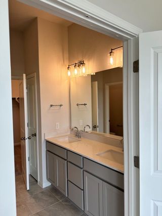 A modern bathroom featuring dual vanities, sleek gray cabinets, and elegant lighting.