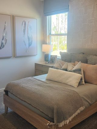 A cozy bedroom with contemporary art, textured wallpaper, and natural light. Modern décor creating a serene ambiance.