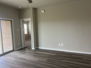 A bright room with laminate flooring, neutral walls, and sliding glass doors leading to a brick patio.