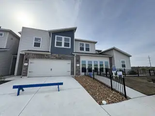 Street view A modern home with gray siding and brick accents in Homestead Village by Meritage Homes (Round Rock, TX).