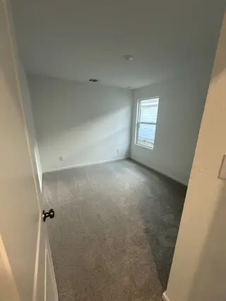 A cozy, carpeted room with bright natural light and a modern design.